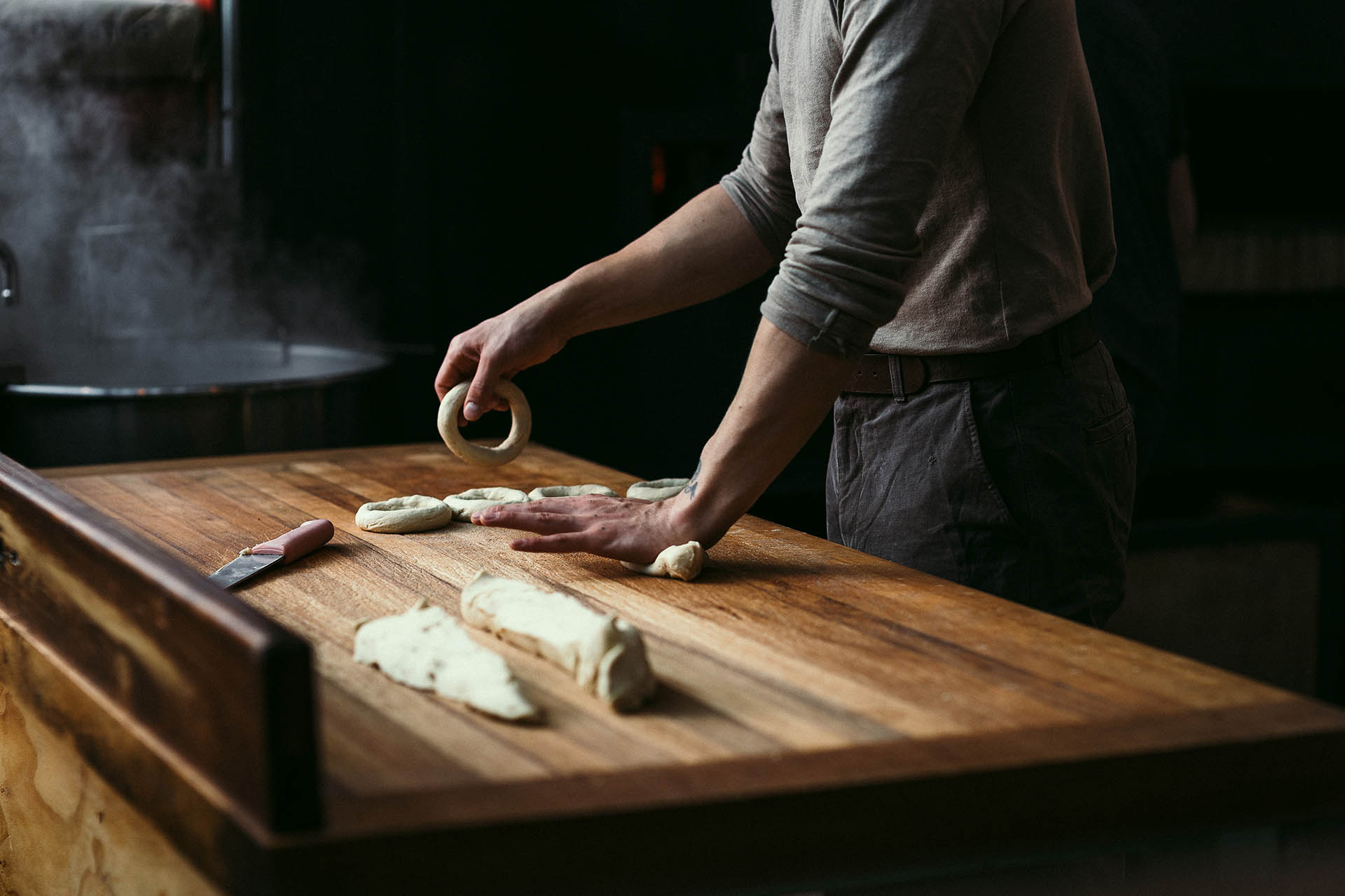 bagel making on a wooden chopping board with boiled pot
