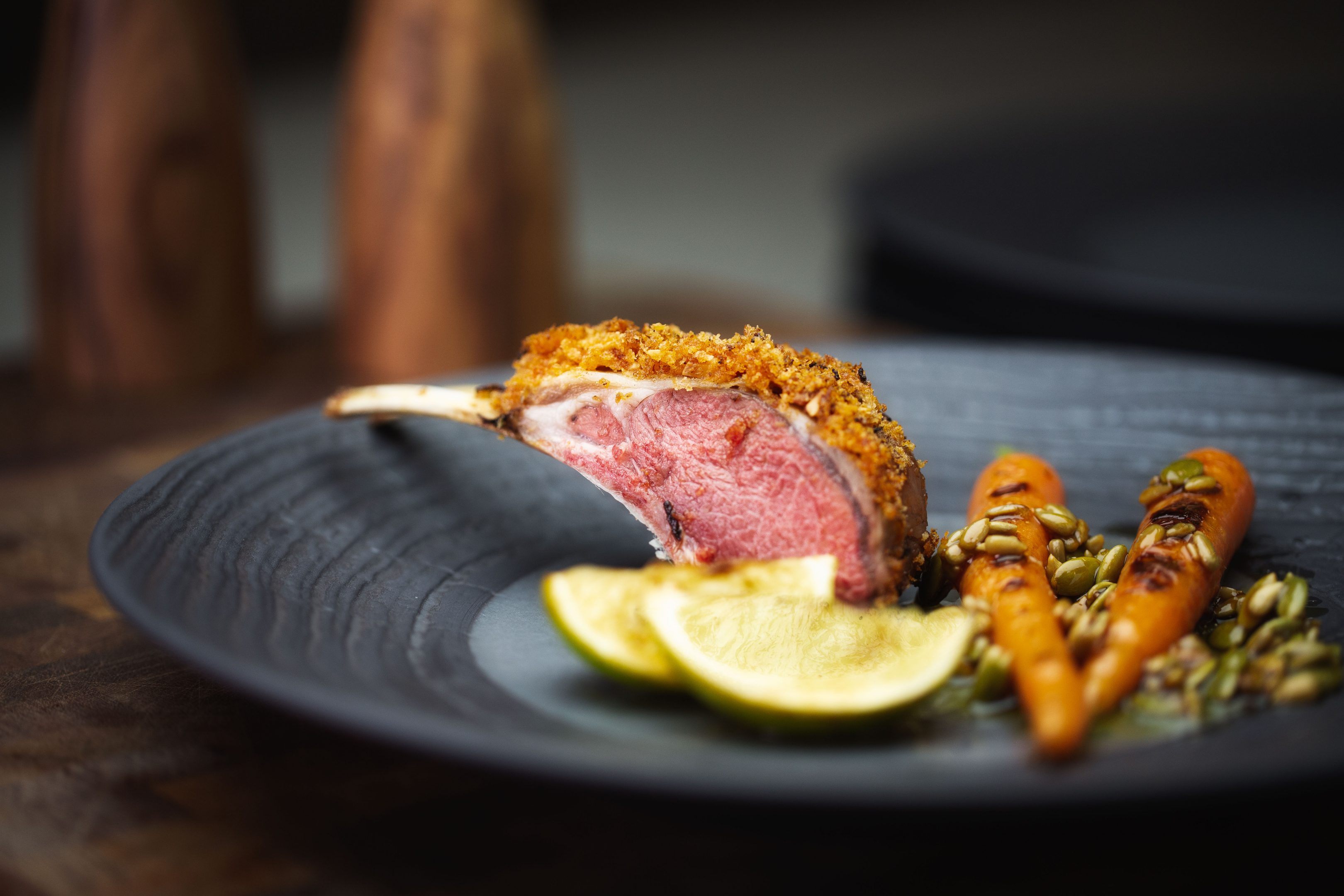 crusted lamb with roasted baby carrots wedged lime